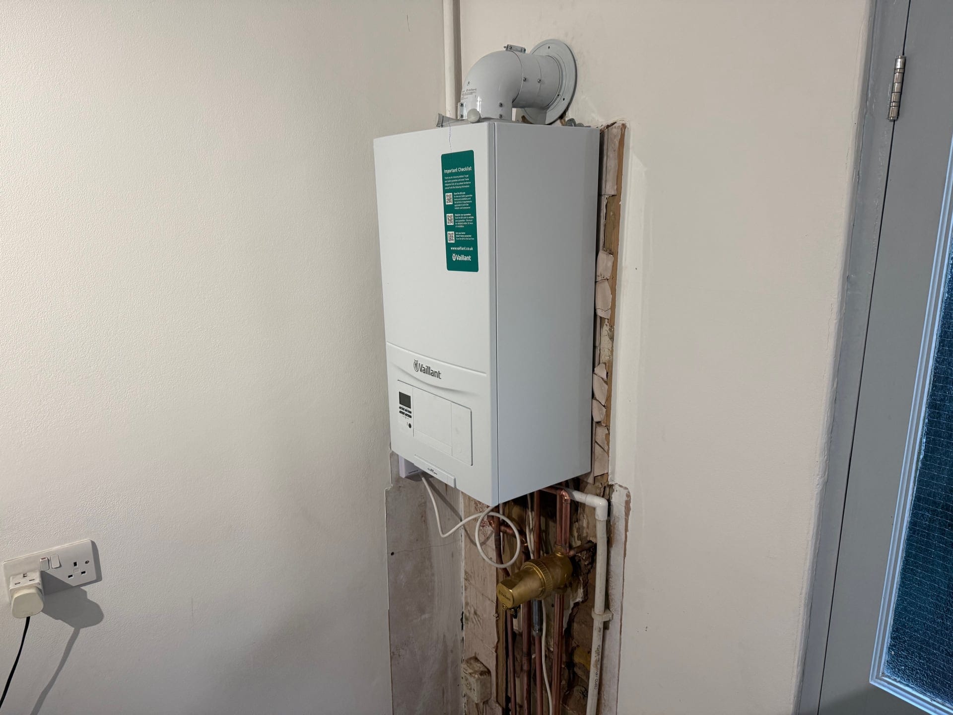 Newly installed Vaillant combi boiler with its flue and copper pipework in a London home